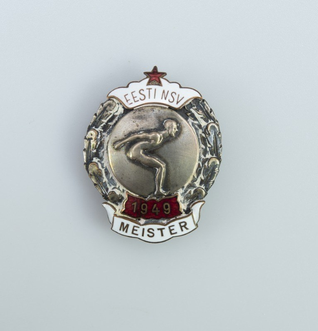 Ein silbernes Abzeichen mit einem roten Stern und Text, Emblem der deutschen Olympischen Spiele 1949.