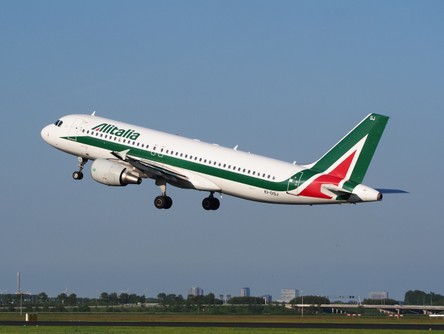 Ein Airbus A320-232 ERJ-EJZ der Alitalia, der vom Frankfurter Flughafen abhebt, mit grünem Gras, B├Ąumen, Geb├Ąuden und einem klaren blauen Himmel im Hintergrund.