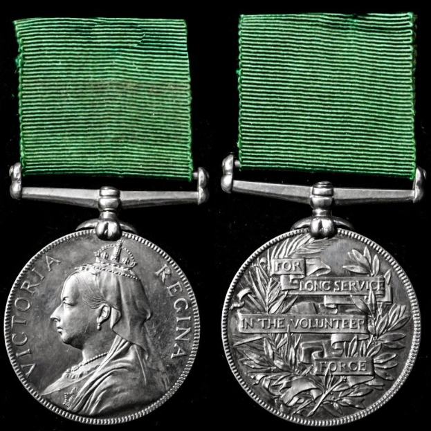 Zwei silberne Medaillen mit grünen Bändern auf schwarzem Hintergrund, eine mit einer Person und die andere mit eingravierter Schrift.