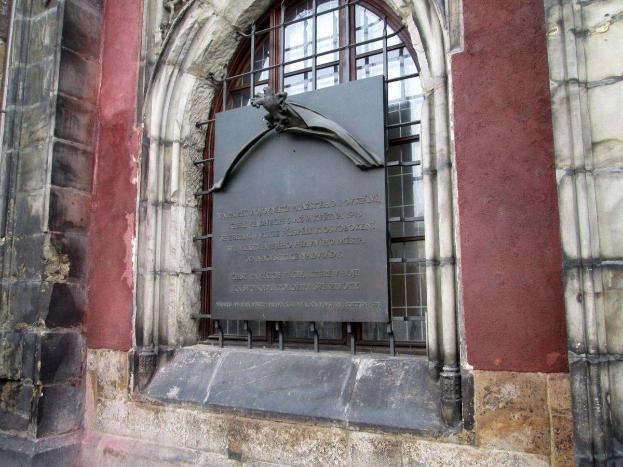 Steinbau mit einem Fenster und einer Holocaust-Gedenktafel mit Inschrift.