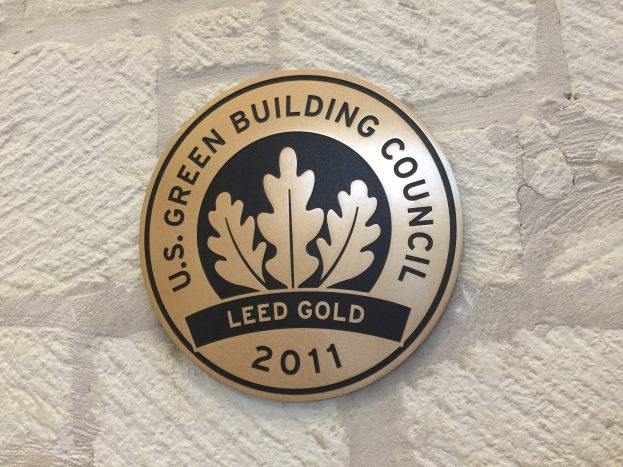 Logo der U.S. Green Building Council an der Seite eines Gebäudes, mit einem grünen Schild mit weißer Umrandung, schwarzer Schrift und einem umgebenden Lorbeerkranz.