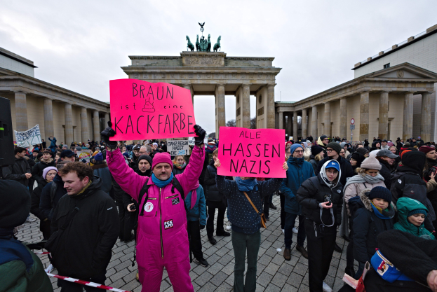 Eine Gruppe von Menschen protestiert vor dem Reichstagsgebäude in Berlin und hält Schilder gegen die Anti-Nazi-Bewegung der deutschen Regierung.