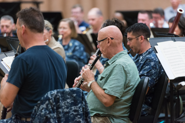 Eine Gruppe von Männern, die Klarinetten spielen, in einem Raum mit Notenständern vor ihnen.