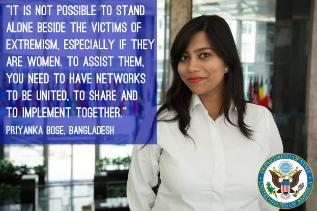 Eine Frau in einem weißen Hemd steht vor einem Gebäude mit einem Zitat über die Unterstützung von Opfern von Extremismus, mit einem Logo in der rechten unteren Ecke.