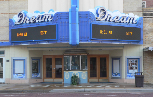 Außenansicht des Dream Theaters in St. Louis, Missouri, mit Glastüren und -fenstern, einem Namen-Schild, einem Müllbehälter, einer Topfpflanze und einer Straße unten.