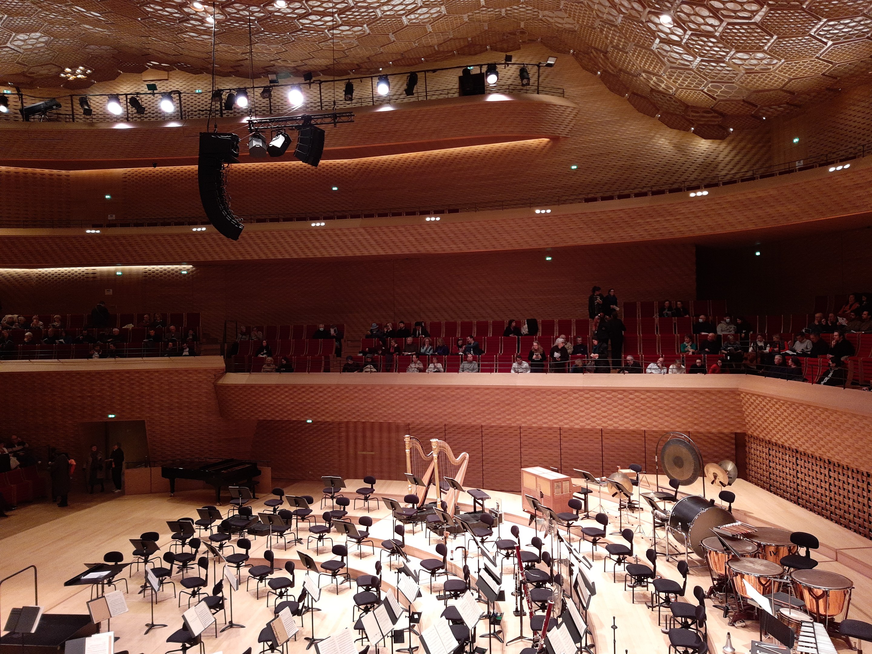 Großer Auditorium mit Musikinstrumenten, Stühlen, Ständern und Menschen, mit beleuchteter Decke im Berliner Philharmoniker.