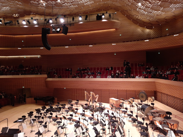 Großer Auditorium mit Musikinstrumenten, Stühlen, Ständern und Menschen, mit beleuchteter Decke im Berliner Philharmoniker.