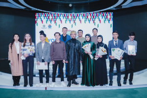 Eine Gruppe von Menschen auf einer Bühne mit Blumensträußen und Zertifikaten, im Hintergrund ein "Youth Solar Awards 2019"-Plakat.