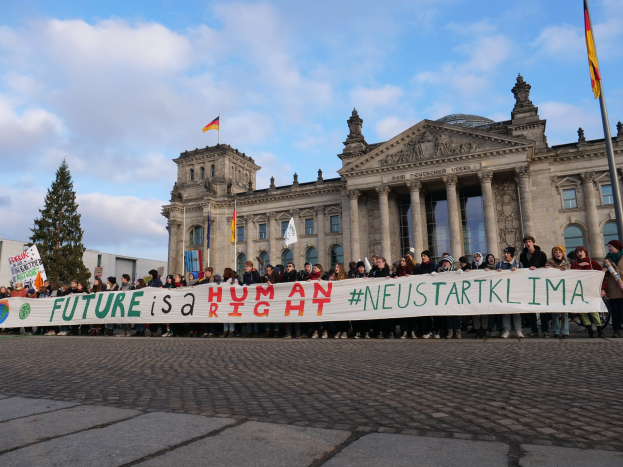 Gruppe von Menschen vor dem Reichstaggebäude in Berlin mit einem Banner mit der Aufschrift "Zukunft ist ein Menschenrecht."