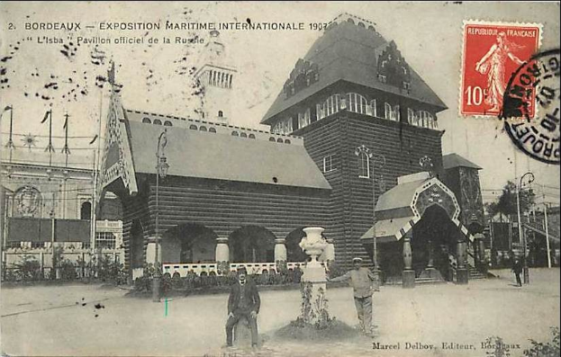 Schwarzes und weißes Foto eines Gebäudes mit einem Brunnen davor, umgeben von Menschen, Mästäben, Flaggen, Bäumen und anderen Gegenständen, mit einem Stempel auf der rechten Seite, der "Exposition Maritime Internationale Bordeaux 1907" lautet.