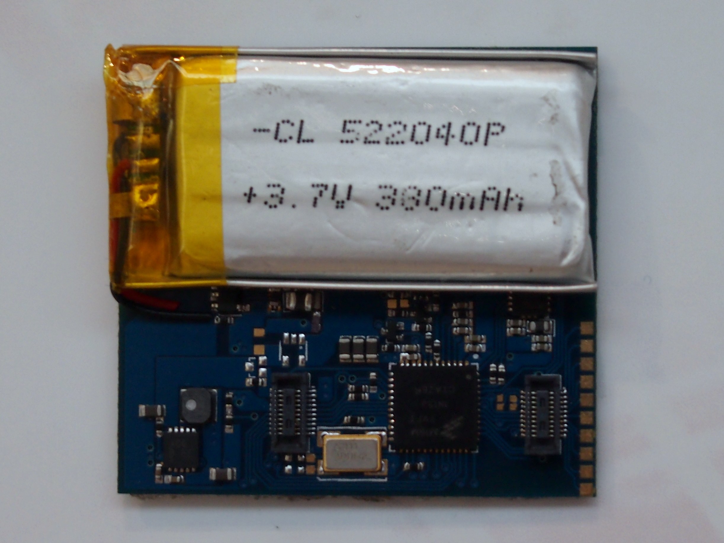 Nahaufnahme einer Mobiltelefonbatterie auf einer Leiterplatte mit aufgedrucktem Text, die auf einer weißen Oberfläche liegt.