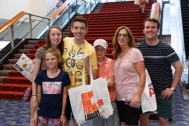 Menschen mit strahlenden Gesichtern und Taschen vor einer Rolltreppe auf der Nationalen Buchmesse 2019.