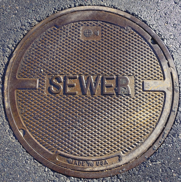 Metall-Schachtdruckgussdeckel auf der Straße mit dem Wort "Kanal" geprägt.