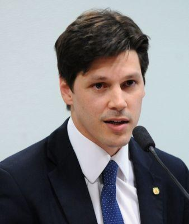 Ein Mann im Anzug spricht in ein Mikrofon auf einem Podium, wahrscheinlich zur Genehmigung eines Gesetzes durch die Regierung.