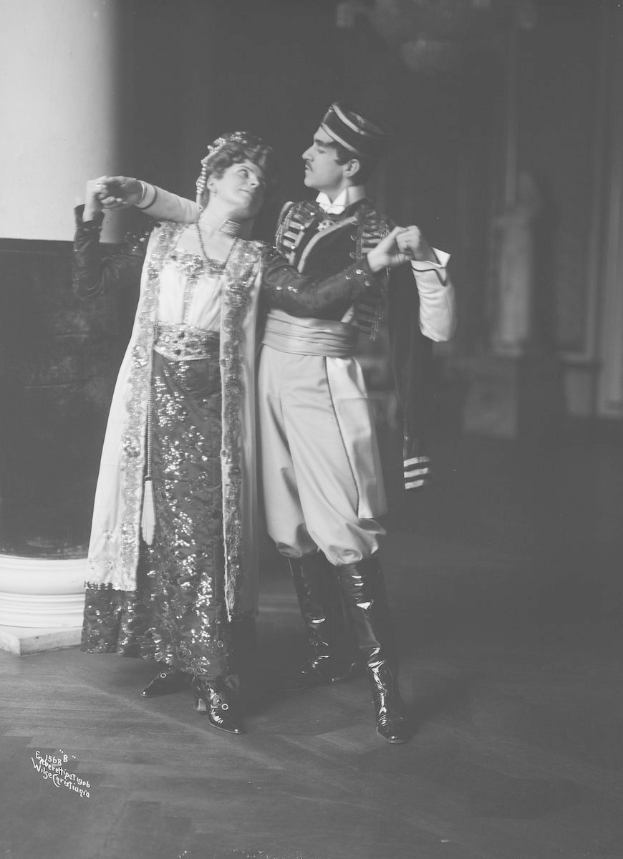 Schwarzes und weißes Foto eines Mannes und einer Frau, die in einem Ballsaal tanzen, mit einer Säule und einer Wand im Hintergrund; der Mann trägt Schuhe, was darauf hindeutet, dass sie performen.