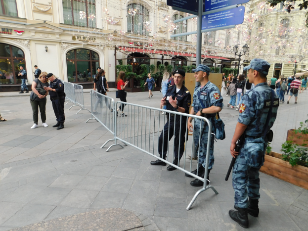 Eine Gruppe von Polizisten steht vor einer Menge, einige halten Waffen, mit Absperrungen und Texttafeln im Vordergrund und Gebäuden, Laternenmasten, Pflanzen und Bäumen im Hintergrund, während eines Anti-Terror-Einsatzes in Wien, Österreich.