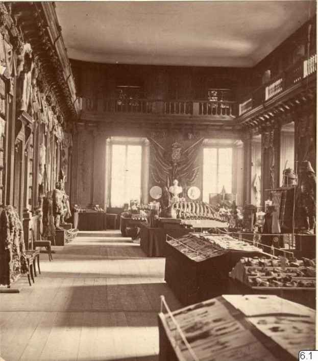 Schwarz-weiß-Fotografie eines Raums im Museum of Fine Arts, London, mit Tischen, Stühlen, Skulpturen an den Wänden, Fenstern mit Vorhängen und Geländern.